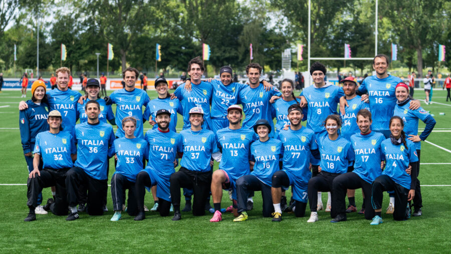 ITA mixed team poses in two lines wearing blue jerseys on a field.