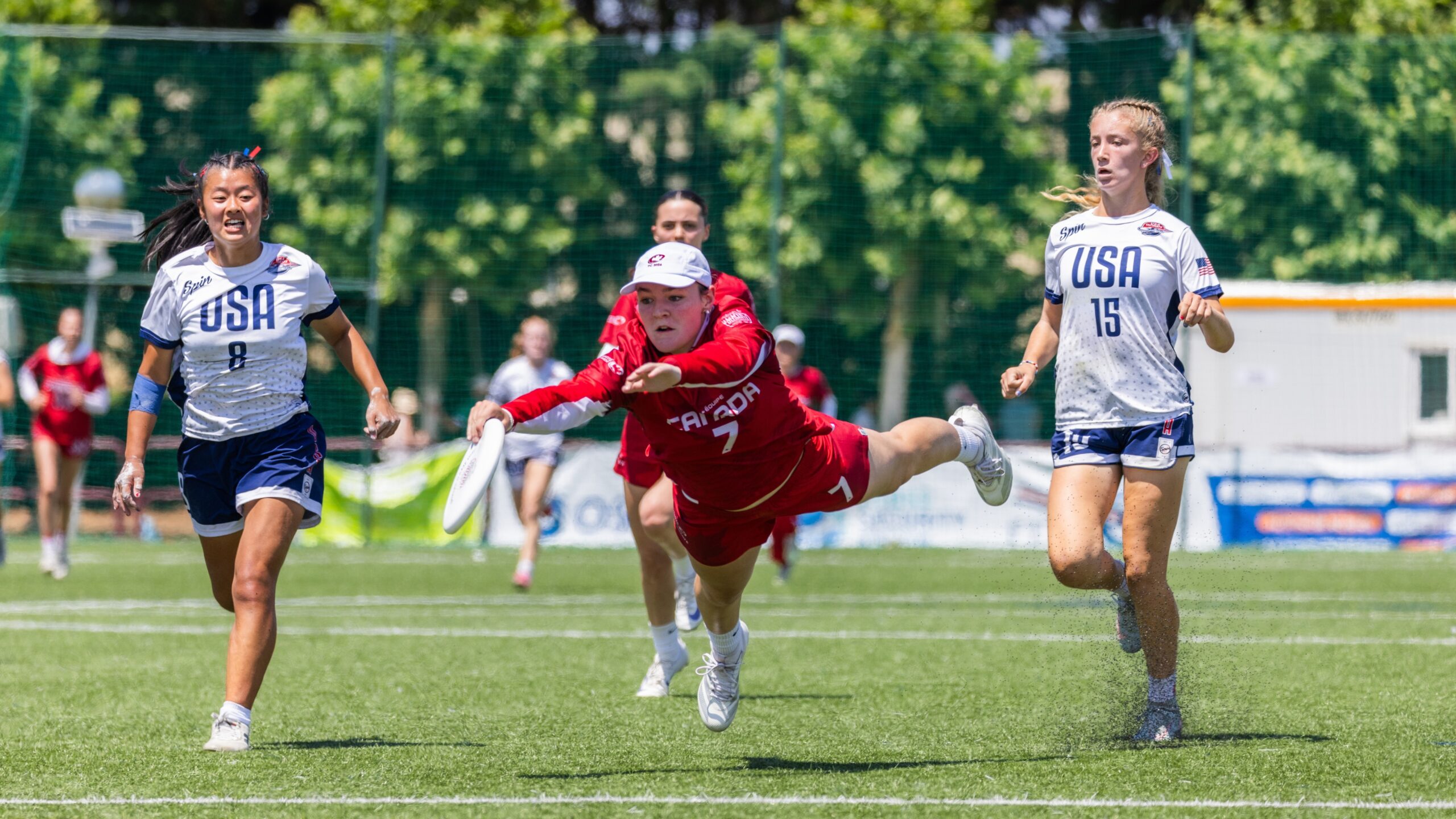 Canada’s player dives horizontally to catch the disc while two USA defenders chase during a fast-paced match at the 2026 World Junior Ultimate Championships.