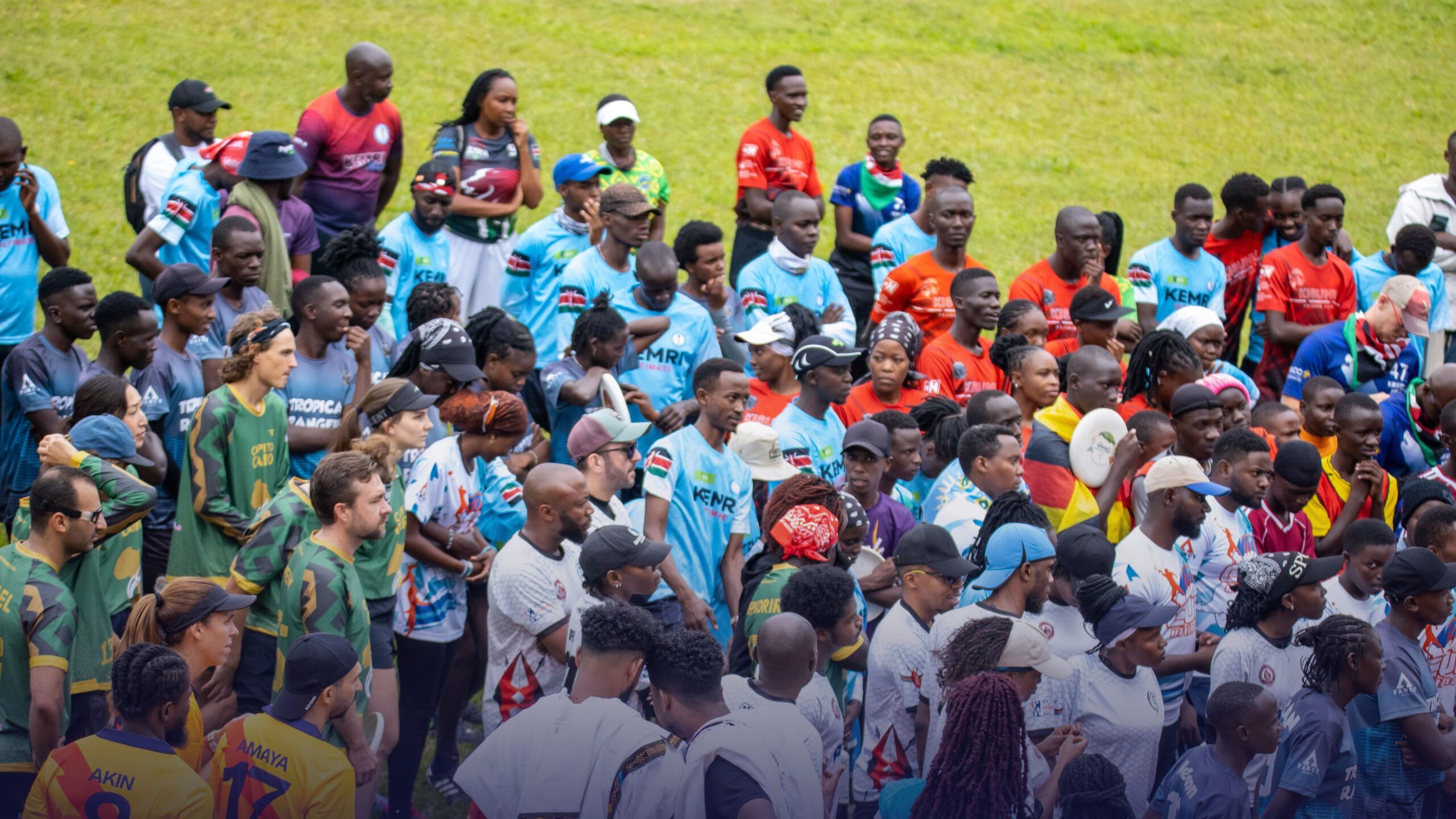 A large group of Flying Disc athletes and participants gathered together on a grassy field during a sporting event in Africa.