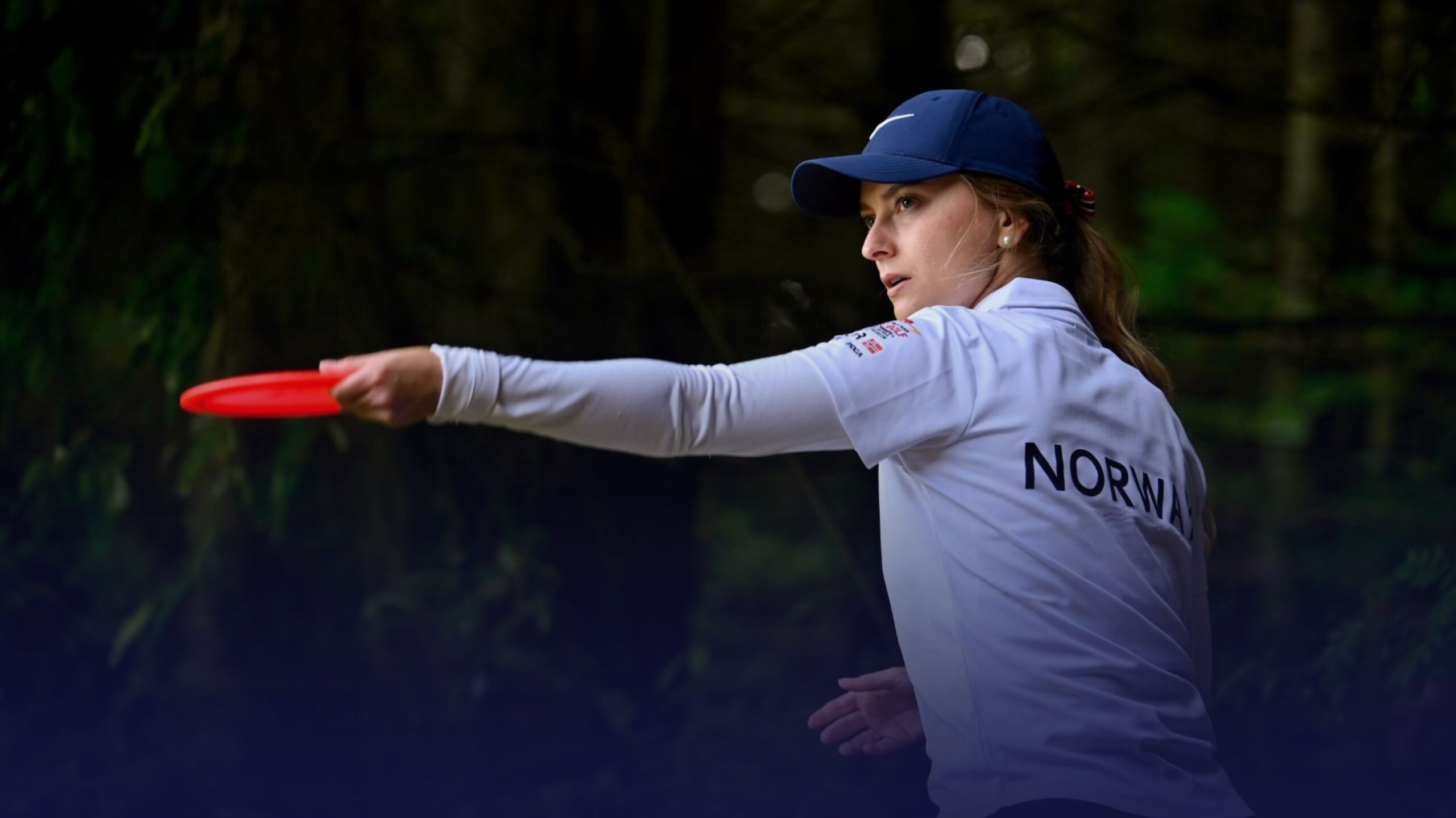 Norwegian player in a white team jersey throws a red disc during the WFDF World Team Disc Golf Championships 2026.